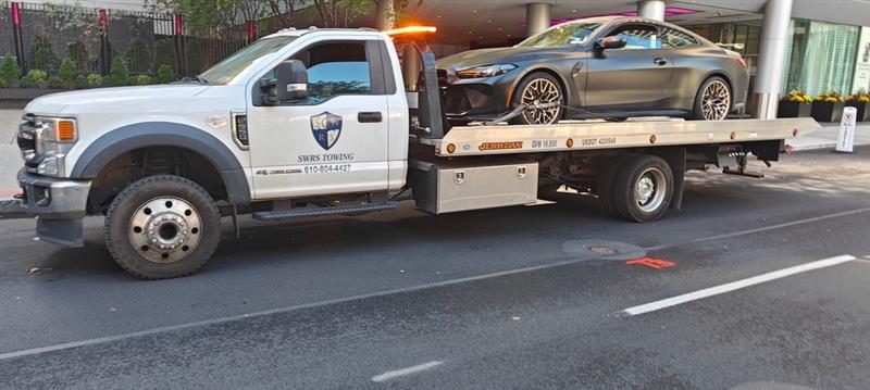 SWRS Towing flatbed with a BMW coupe in the city